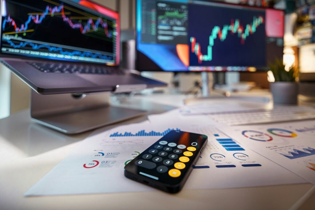 Smartphone and calculator on a desk in front of financial charts
