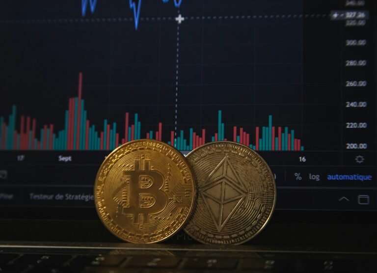Gold and silver crypto coins resting on a laptop keyboard before a trading chart